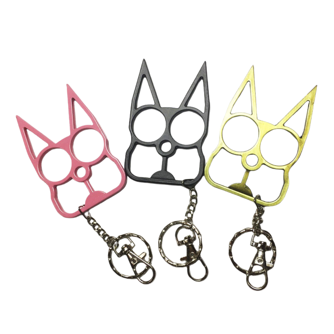 Three metal cat-shaped self-defense keychains in pink, black, and gold, each with a keychain ring and clip, displayed on a white background.
