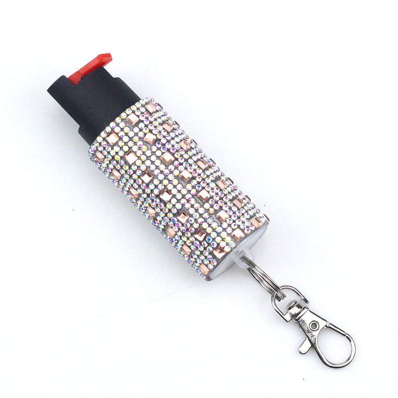 Blistered pepper spray with rhinestone cover and keychain attachment on a white background