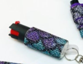 Decorative pepper spray with purple and blue gemstones on a white background