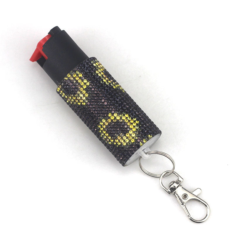 Black pepper spray with decorative yellow pattern and keychain on a white background