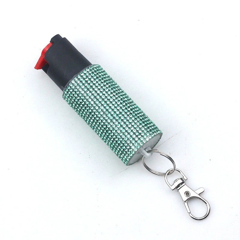 pepper spray with green rhinestone cover and keychain clip on a white background