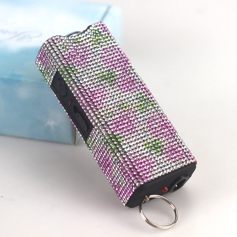 Pink and silver blinged-out flashlight on a white surface with a blurred background