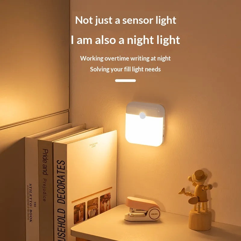 Small sensor light on a wall above a desk with books and a stapler.
