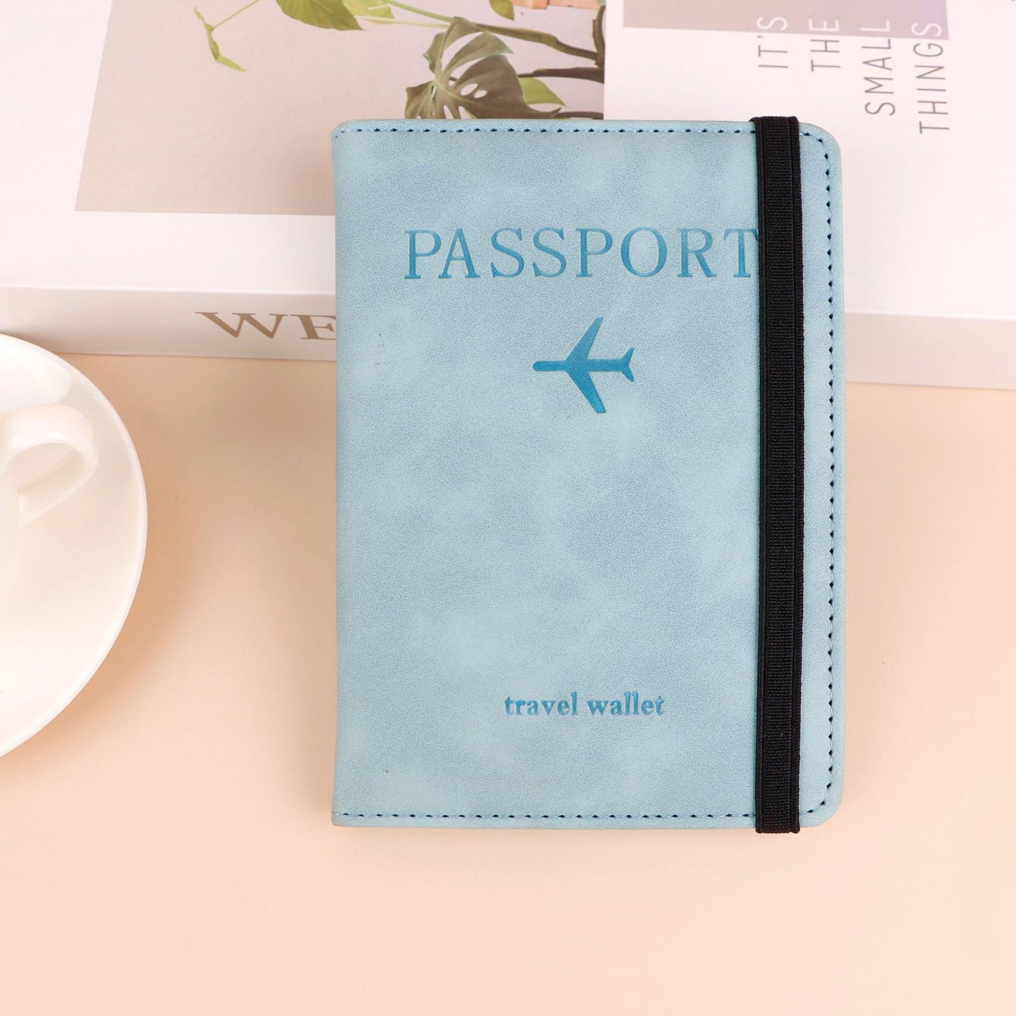 Light blue passport travel wallet with airplane icon on a beige surface