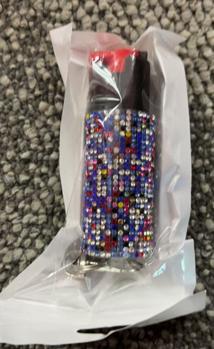 Colorful rhinestone-encrusted pepper spray on a textured surface