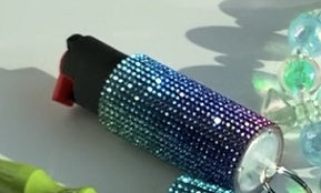 Decorative pepper spray with colorful gemstones on a reflective surface