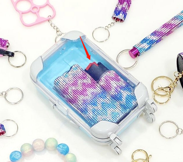 pepper spray with colorful rhinestone design on a white background with various keychains.