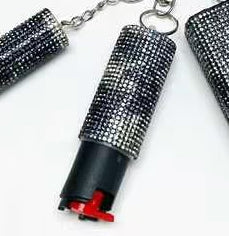 Decorative pepper spray canisters with rhinestone embellishments on a white background