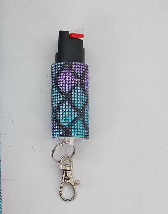 Pepper spray with a decorative case and keychain attachment on a light gray background