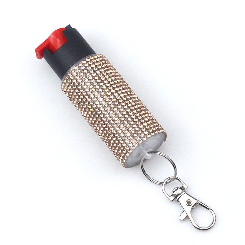 Pepper spray canister with rhinestone cover and keychain on a white background