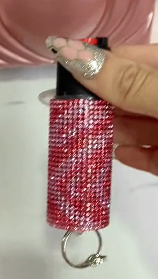 Red glittery keychain held by a hand with a pink background